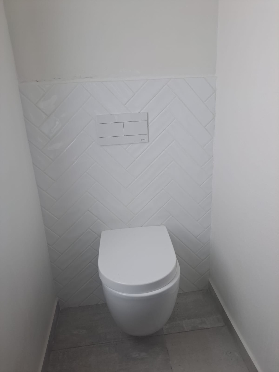 Wall-hung toilet with white herringbone tiling