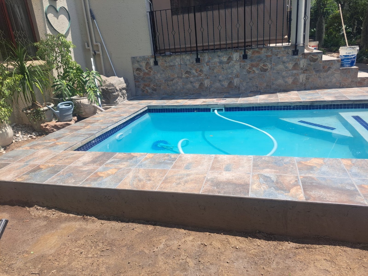 Kidney-shaped pool with brick-edged paving